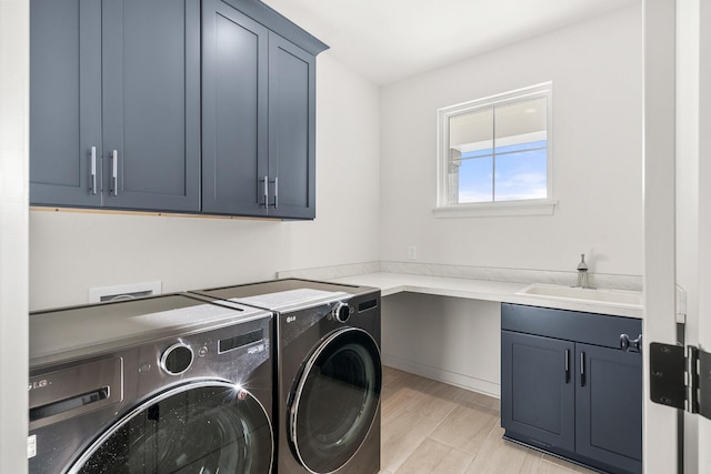 washroom with cabinets, separate washer and dryer, and sink