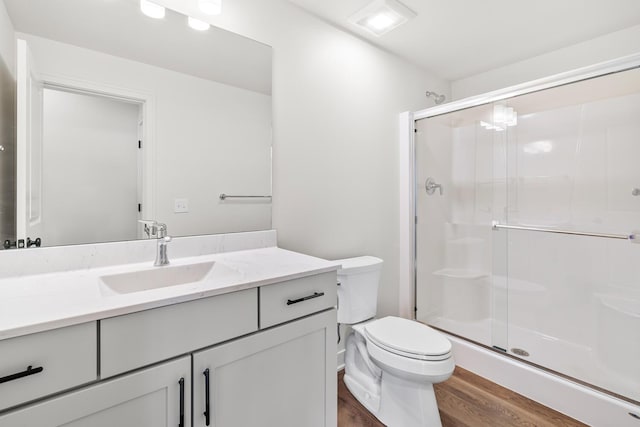 bathroom featuring hardwood / wood-style flooring, vanity, an enclosed shower, and toilet