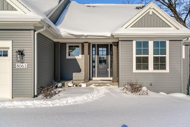 snow covered property entrance featuring a garage