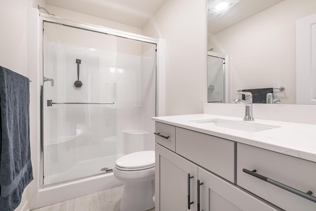 bathroom featuring vanity, a shower with shower door, and toilet