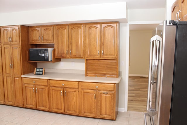 kitchen featuring light tile patterned flooring and stainless steel fridge