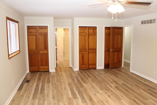 unfurnished bedroom featuring multiple closets, ceiling fan, connected bathroom, and light wood-type flooring