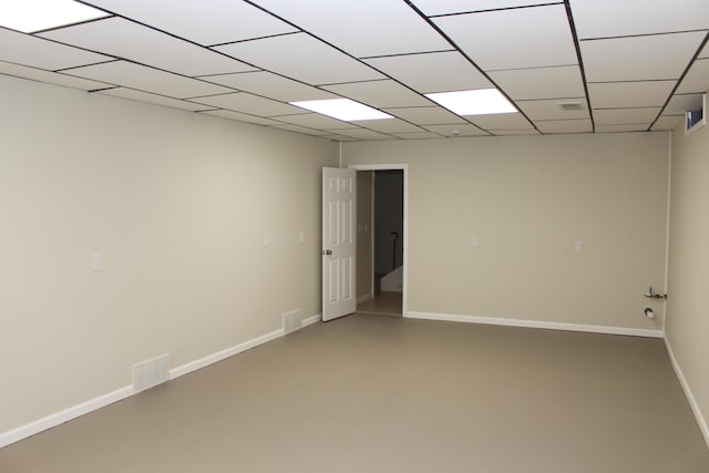 empty room with a paneled ceiling and concrete floors