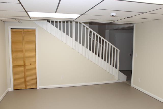 staircase featuring a paneled ceiling and concrete flooring