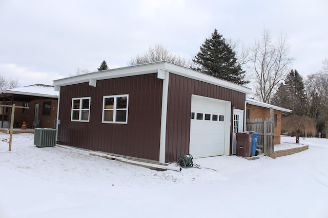 snow covered garage with central air condition unit