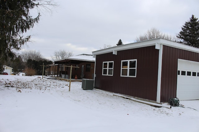 view of snow covered exterior with a garage and central AC unit