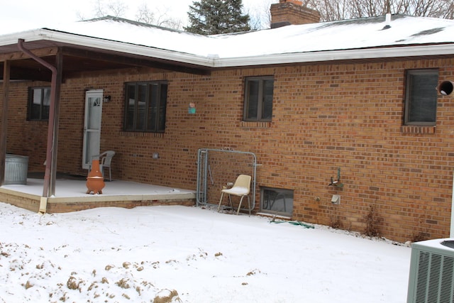 snow covered back of property featuring cooling unit