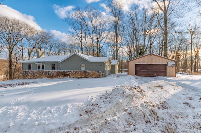 snow covered property with a garage and an outbuilding