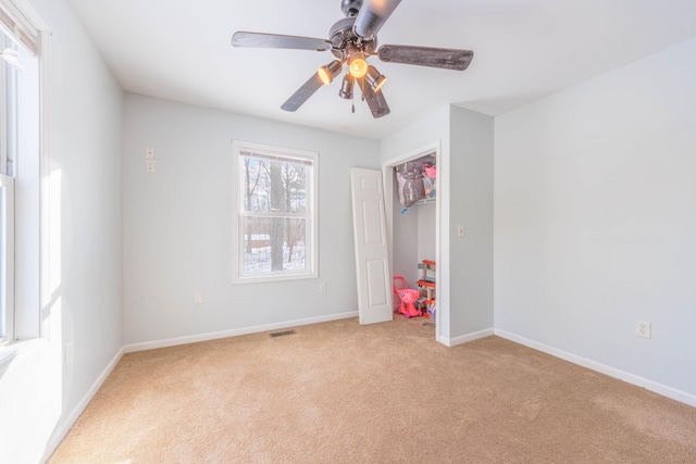 interior space with light colored carpet, ceiling fan, and a closet