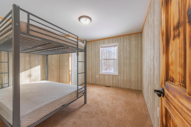 bedroom with light colored carpet and wood walls