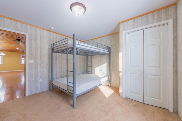 unfurnished bedroom with carpet, wooden walls, and a closet