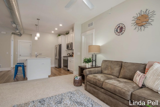living area featuring ceiling fan, visible vents, light wood-style flooring, and recessed lighting