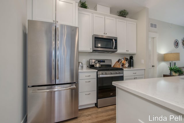 kitchen featuring visible vents, light countertops, light wood-style floors, appliances with stainless steel finishes, and white cabinetry