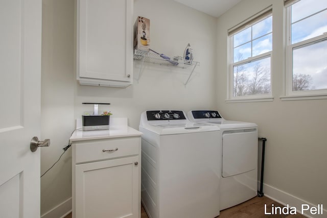laundry room with washer and dryer, baseboards, cabinet space, and wood finished floors