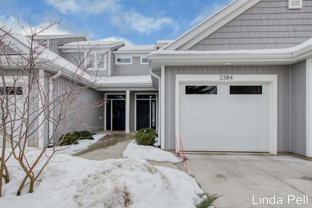 snow covered property entrance with a garage