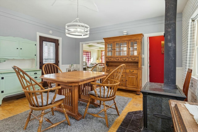 dining space with an inviting chandelier, a healthy amount of sunlight, light parquet floors, and a wood stove