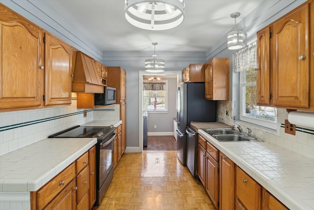 kitchen with premium range hood, decorative light fixtures, appliances with stainless steel finishes, tile counters, and decorative backsplash