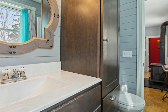 bathroom with vanity, parquet floors, wooden walls, and toilet