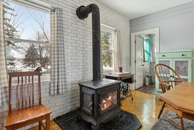 living area featuring brick wall, light parquet floors, and a wood stove