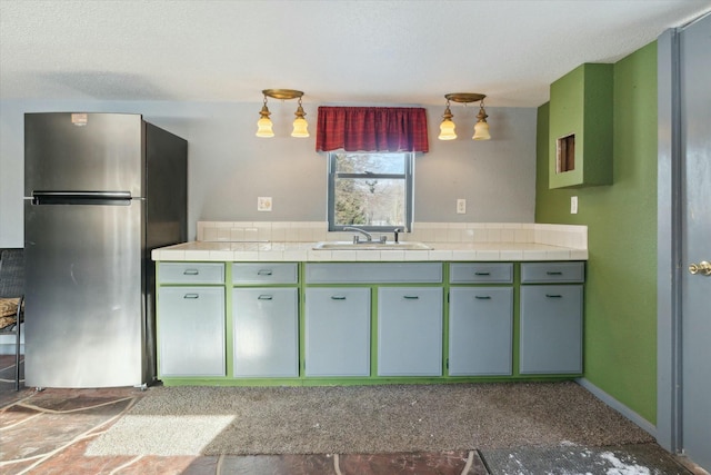 kitchen featuring sink, tile countertops, and stainless steel fridge