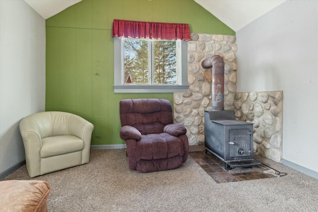 sitting room with lofted ceiling, a wood stove, and carpet