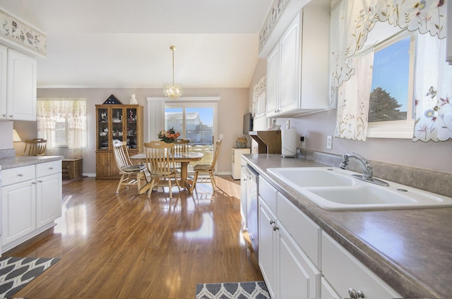 kitchen featuring pendant lighting, sink, white cabinetry, an inviting chandelier, and dark hardwood / wood-style flooring