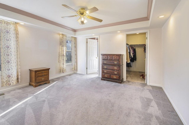 unfurnished bedroom with ornamental molding, a walk in closet, light colored carpet, ceiling fan, and a closet