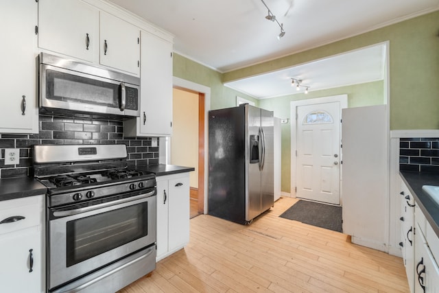 kitchen with tasteful backsplash, white cabinets, light hardwood / wood-style floors, stainless steel appliances, and track lighting