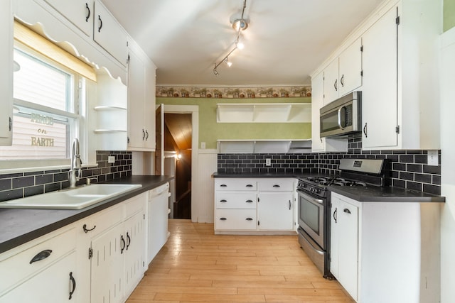 kitchen with sink, backsplash, stainless steel appliances, white cabinets, and light wood-type flooring