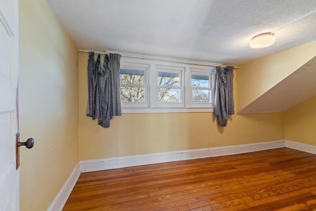 additional living space featuring hardwood / wood-style flooring and a textured ceiling