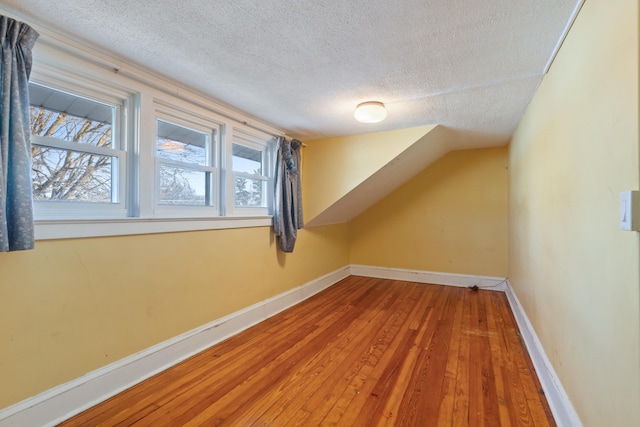 additional living space with hardwood / wood-style flooring and a textured ceiling