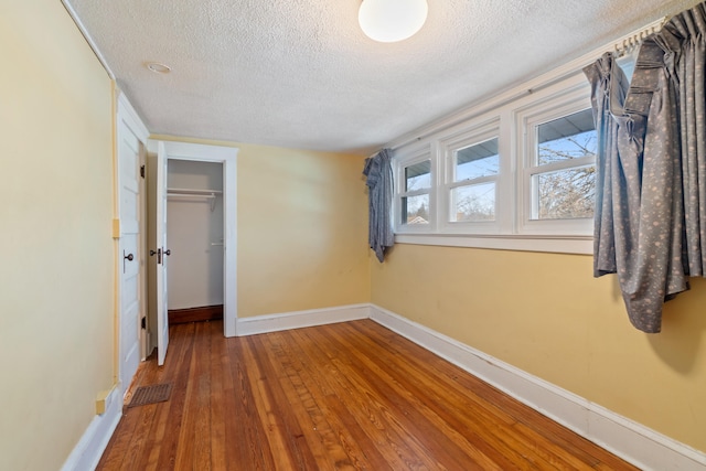 unfurnished bedroom with hardwood / wood-style flooring, a closet, and a textured ceiling