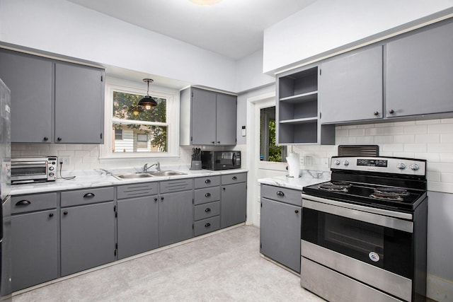 kitchen featuring stainless steel electric stove, decorative light fixtures, sink, gray cabinetry, and plenty of natural light