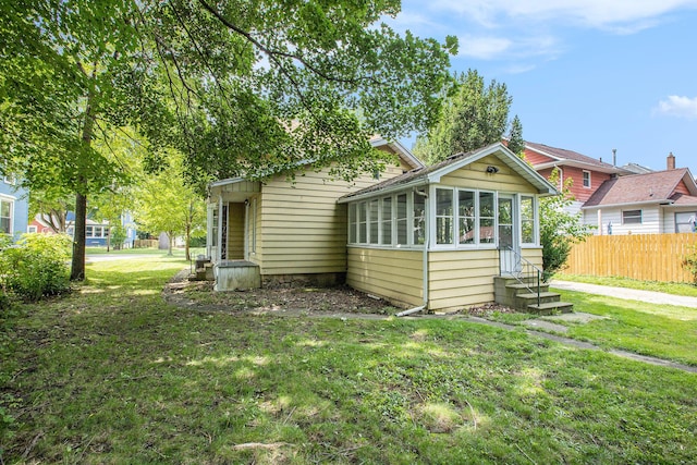 back of property featuring a sunroom and a lawn