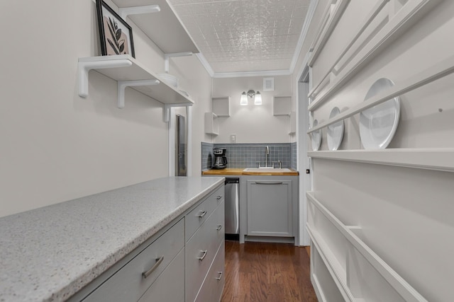 kitchen with sink, light stone counters, crown molding, dark hardwood / wood-style floors, and decorative backsplash