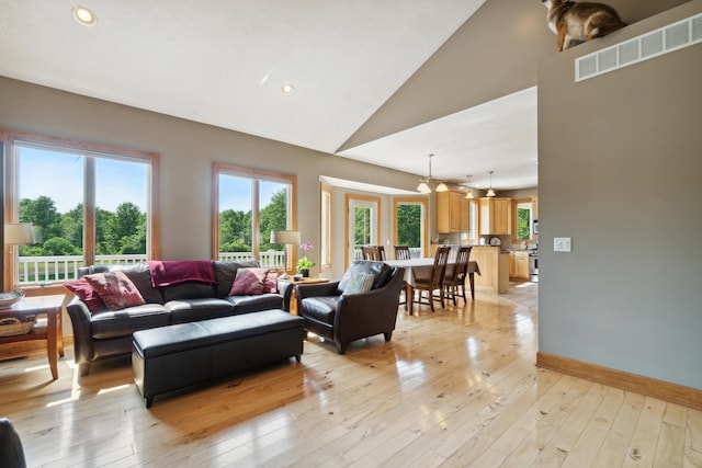 living room featuring high vaulted ceiling and light hardwood / wood-style floors