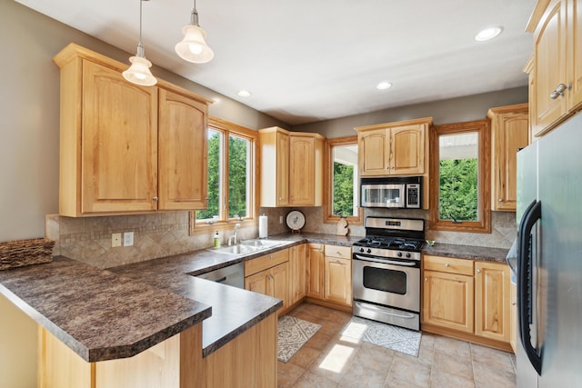 kitchen featuring sink, appliances with stainless steel finishes, hanging light fixtures, tasteful backsplash, and kitchen peninsula