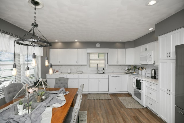 kitchen with dark wood-type flooring, sink, hanging light fixtures, white appliances, and white cabinets