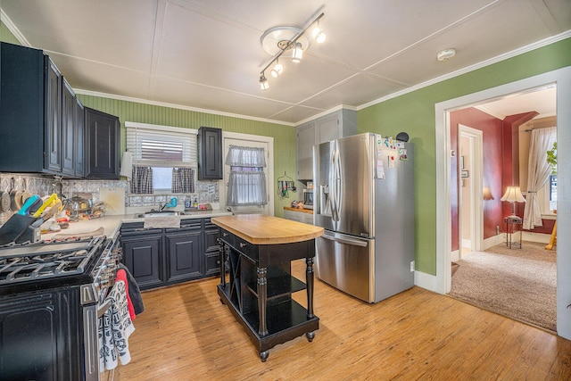 kitchen with wood counters, crown molding, a kitchen island, stainless steel appliances, and light hardwood / wood-style floors