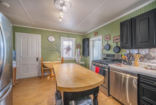 kitchen with ornamental molding, appliances with stainless steel finishes, and light hardwood / wood-style flooring