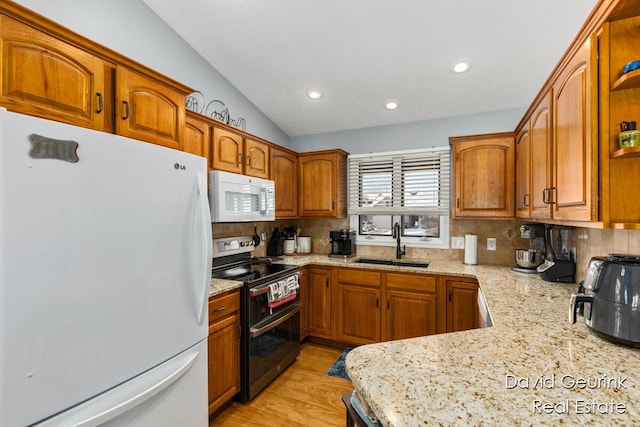 kitchen featuring white appliances, a sink, light stone countertops, tasteful backsplash, and brown cabinetry