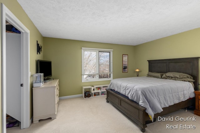 bedroom featuring light carpet, a textured ceiling, and baseboards