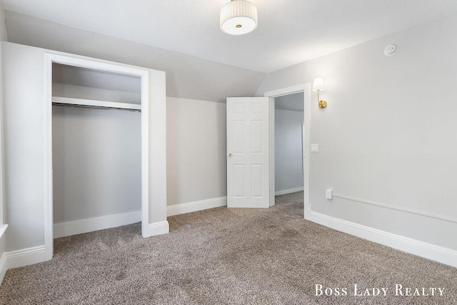 unfurnished bedroom with lofted ceiling, carpet flooring, and a closet