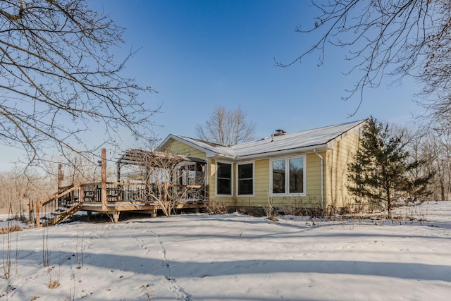 snow covered house featuring a pergola and a deck