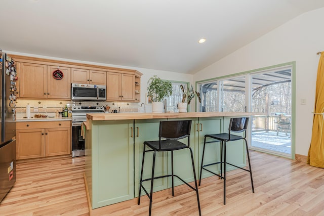 kitchen featuring stainless steel appliances, lofted ceiling, a wealth of natural light, and backsplash