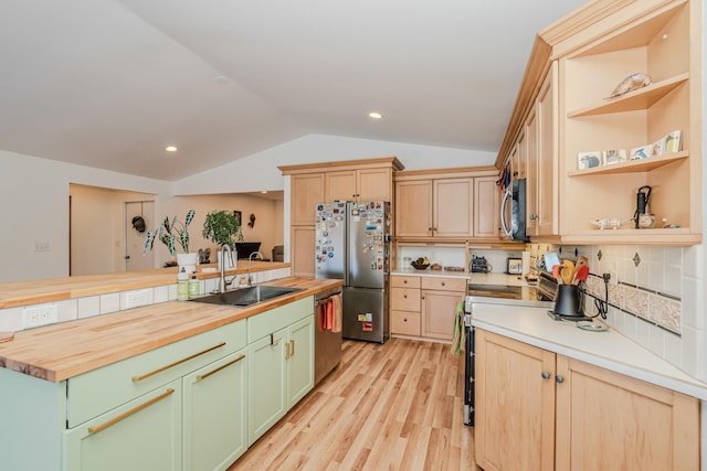 kitchen with lofted ceiling, butcher block countertops, sink, light hardwood / wood-style flooring, and appliances with stainless steel finishes