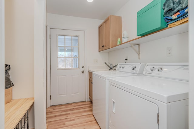 clothes washing area with cabinets, sink, light hardwood / wood-style floors, and washing machine and dryer