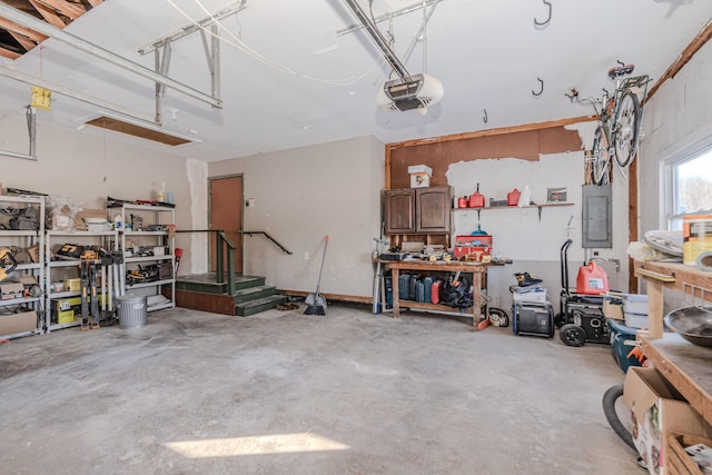 garage with a garage door opener, electric panel, and a workshop area