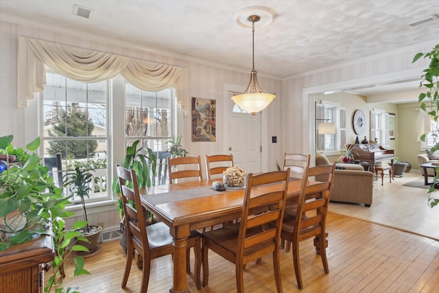 dining room with crown molding and light hardwood / wood-style flooring