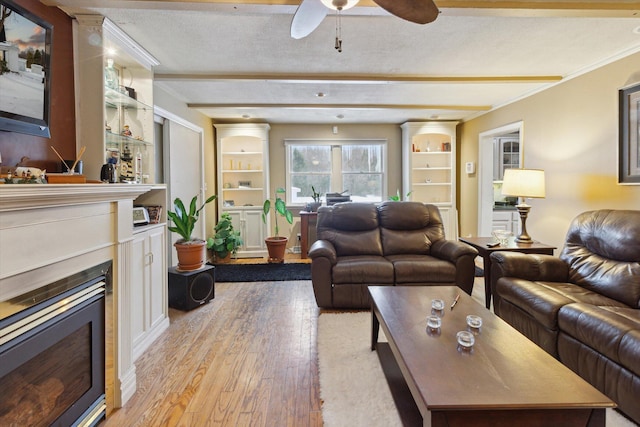 living room featuring light hardwood / wood-style flooring, built in features, and a textured ceiling